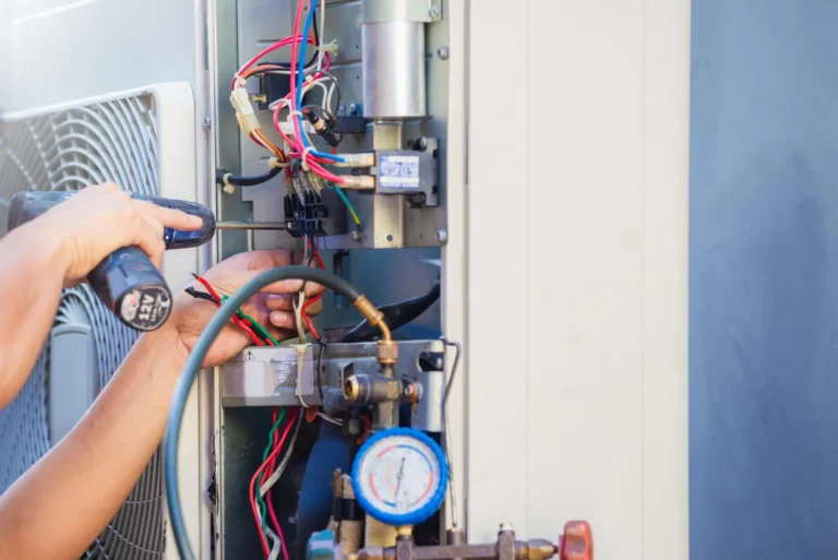 A person uses a screwdriver and tool to work on the exposed wiring and components inside an air conditioning unit during routine AC maintenance for Horizon Air.