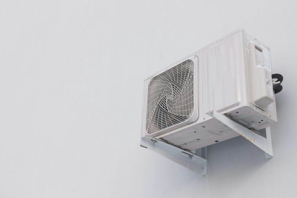 A wall-mounted outdoor air conditioning unit with a visible fan and support brackets, attached to a plain white wall—ideal for Horizon Air AC maintenance or repair needs.