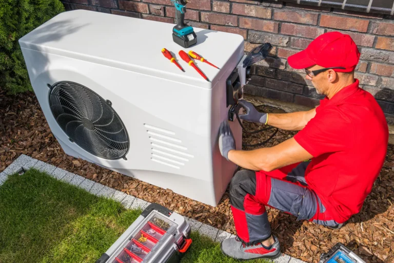 A technician in red work clothes installs or repairs an outdoor heat pump unit next to a brick wall, with tools and a toolbox nearby, performing expert AC Maintenance for Horizon Air.